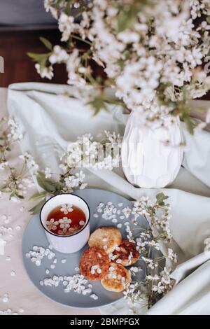 Frühstück am Morgen, getoastete schöne Käsekuchen auf einem Teller auf der Tischdecke neben einem Frühlingsstrauß aus weißen Blumen Stockfoto