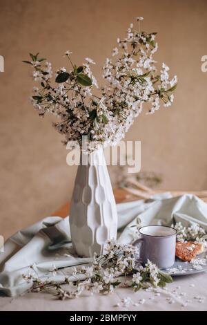 Frühstück am Morgen, getoastete schöne Käsekuchen auf einem Teller auf der Tischdecke neben einem Frühlingsstrauß aus weißen Blumen Stockfoto