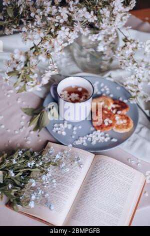 Frühstück am Morgen, getoastete schöne Käsekuchen auf einem Teller auf der Tischdecke neben einem Frühlingsstrauß aus weißen Blumen Stockfoto