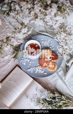Frühstück am Morgen, getoastete schöne Käsekuchen auf einem Teller auf der Tischdecke neben einem Frühlingsstrauß aus weißen Blumen Stockfoto