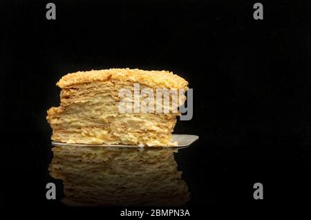 Stück Kuchen napoleon mit Reflexion auf schwarzem Hintergrund. Stockfoto