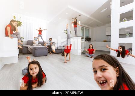 Erschöpft junge Eltern sitzen auf Couch in der Küche fühlen sich unwohl müde von schlecht erzogene laute kleine Kinder laufen spielen, krank genervte Mutter oder Kindermädchen Stockfoto