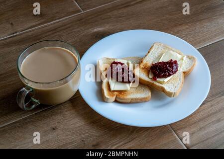 Tasse Kaffee mit Milch und zwei Scheiben gerösteten Sandwich-Brot mit Butter und Himbeere. Frühstück mit Kaffee. Seitenansicht. Freier Platz für Text. Stockfoto