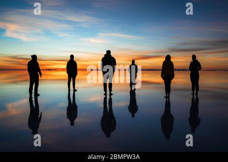 Gruppe von Reisenden Silhouette gegen Sonnenaufgang in Uyuni Salt Flats (Spanisch: Salar de Uyuni ) in Bolivien, Teamwork und Führungskonzept. Stockfoto