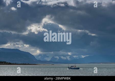 Fischerboot in der Bucht der letzten Hoffnung mit dunklen Wolken, Fjordo Ultima Esperanza, Puerto Natales, Region de Magallanes y de la Antartica Chilena Stockfoto