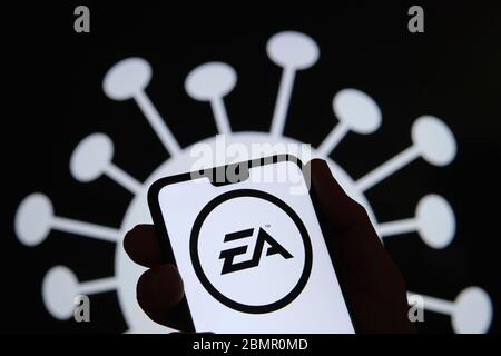 Electronic Arts (EA)-Logo auf einer Smartphone-Silhouette in der Hand halten. Coronavirus-Bild auf dem verschwommenen Hintergrund. Echtes Foto, keine Montage. Stockfoto