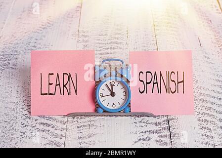 Schreibnotiz, der Spanisch lernen zeigt. Geschäftskonzept für die Übersetzung Sprache in Spanien Wortschatz Dialektsprache Mini blauen Wecker steht oben Stockfoto
