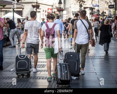 BELGRAD, SERBIEN - 11. JULI 2018:Gruppe junger Reisender, die mit ihren Koffern in der Kneza Mihalova Straße mitten im Publikum spazieren. Der Sockel Stockfoto