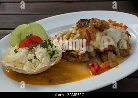 Nahaufnahme von gebackenem Schnitzel Fleisch mit Pilzen und Sauce auf weißem Teller. Restaurantmahlzeit Stockfoto