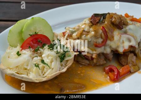 Nahaufnahme von gebackenem Schnitzel Fleisch mit Pilzen und Sauce auf weißem Teller. Restaurantmahlzeit Stockfoto