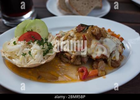 Nahaufnahme von gebackenem Schnitzel Fleisch mit Pilzen und Sauce auf weißem Teller. Restaurantmahlzeit Stockfoto