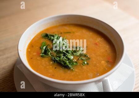 Sahne Suppe mit grünen Kräutern in weißer Schüssel auf einem Teller garniert Stockfoto