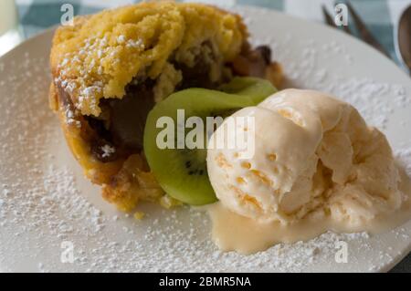 Beerenbrösel mit Kugel Vanilleeis und Kiwi-Frucht auf Retro-Tischtuch Stockfoto