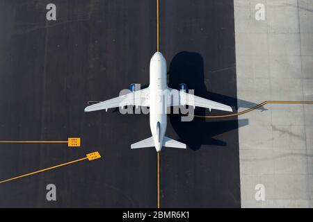 Luftaufnahme mittelweißer Flugzeuge mit Flughafenrichtungslinien als Hintergrund. Nicht identifiziertes Flugzeug von oben gesehen. Platz für Text. Stockfoto