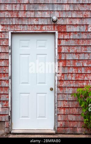 Malerische Fischerhütte, am Dock. façade Details mit Eingangstür auf verwittertem, rot lackiertem Schindelgleis. North Rustico Harbour, PEI, Kanada Stockfoto