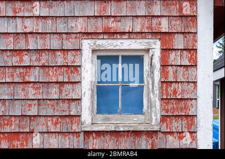 Malerische Fischerhütte, am Dock. façade Details mit kleinem Fenster auf verwittertem, rot lackiertem Schindelgleis. North Rustico Harbour, PEI, Kanada Stockfoto