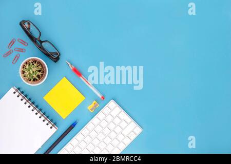 Flaches Lay aus Büromaterial auf blauem Hintergrund mit Kopierfläche. Heimarbeit und Telearbeit. Stockfoto