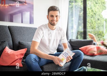 Haan, Deutschland. Mai 2020. Tim Nießner sitzt mit seinem Buch "die geheimen Tricks der 1.0 Schüler" auf einer Couch. Der 18-Jährige aus Haan bei Düsseldorf hat sich etwas Besonderes einfallen lassen, um sich auf sein Abitur vorzubereiten: Er hat fast 100 der besten Abiturienten Deutschlands interviewt, um herauszufinden, was er von ihnen lernen kann. Daraus entstand ein 300-seitiges Buch mit dem Titel: "Die geheimen Tricks der 1,0er-Schüler" 1.0, das am 12.05.2020 im mvg Verlag erscheinen wird. Bild: Marcel Kusch/dpa/Alamy Live News Stockfoto