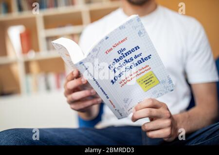 Haan, Deutschland. Mai 2020. Tim Nießner sitzt mit seinem Buch "die geheimen Tricks der 1.0 Schüler" auf einer Couch. Der 18-Jährige aus Haan bei Düsseldorf hat sich etwas Besonderes einfallen lassen, um sich auf sein Abitur vorzubereiten: Er hat fast 100 der besten Abiturienten Deutschlands interviewt, um herauszufinden, was er von ihnen lernen kann. Daraus entstand ein 300-seitiges Buch mit dem Titel: "Die geheimen Tricks der 1,0er-Schüler" 1.0, das am 12.05.2020 im mvg Verlag erscheinen wird. Bild: Marcel Kusch/dpa/Alamy Live News Stockfoto