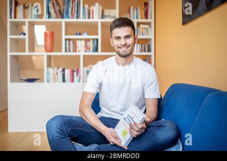 Haan, Deutschland. Mai 2020. Tim Nießner sitzt mit seinem Buch "die geheimen Tricks der 1.0 Schüler" auf einer Couch. Der 18-Jährige aus Haan bei Düsseldorf hat sich etwas Besonderes einfallen lassen, um sich auf sein Abitur vorzubereiten: Er hat fast 100 der besten Abiturienten Deutschlands interviewt, um herauszufinden, was er von ihnen lernen kann. Daraus entstand ein 300-seitiges Buch mit dem Titel: "Die geheimen Tricks der 1,0er-Schüler" 1.0, das am 12.05.2020 im mvg Verlag erscheinen wird. Bild: Marcel Kusch/dpa/Alamy Live News Stockfoto