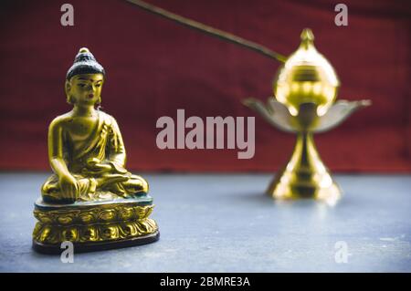 Nahaufnahme Stillleben von antikem meditierenden Buddha und Glocke auf rustikalem Boden. Glaube, Tradition, Spiritualität, Gebet, Symbole des Friedens und religiöse sie Stockfoto