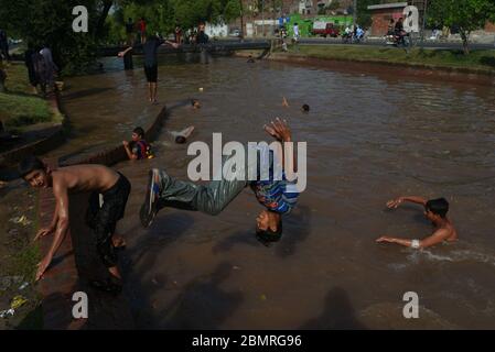 Lahore, Pakistan. Mai 2020. Pakistanische Jugendliche genießen Bad im Kanalwasser, um die Hitze zu schlagen und etwas Erleichterung von warmem Wetter in Ramazan-ul-Mubarak in Lahore. (Foto von Rana Sajid Hussain/Pacific Press) Quelle: Pacific Press Agency/Alamy Live News Stockfoto