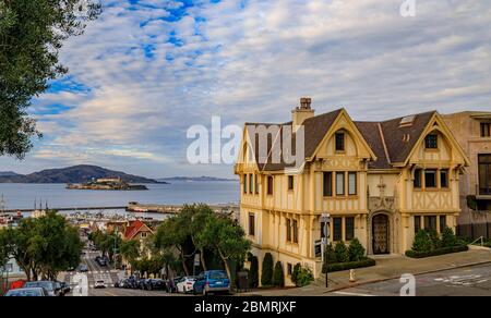 Cable Car-Spuren auf der Hyde Street neben einem Tudor-Haus, mit der berühmten Gefängnisinsel Alcatraz im Hintergrund in San Francisco, Kalifornien, USA Stockfoto