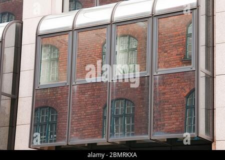 Alte Gebäudearchitektur spiegelt sich in einem modernen Gebäude wider. Vorderansicht des Gebäudes. München, Deutschland. Stockfoto