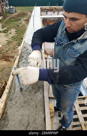 Arbeiter machen Beton in Schalung mit Trowel, Bau eines neuen Hauses.2020 Stockfoto