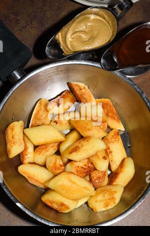 Gebratene Kartoffelknödel in einer Pfanne mit Würstchen, gebratenen Zwiebeln, Käsesauce serviert. Restaurant Tischgedeckten, polnisches Abendessen Konzept Stockfoto