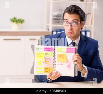 Die jungen gutaussehenden Mitarbeiter Planung seine Tätigkeit Stockfoto