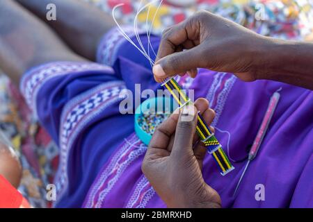 Herstellung von handgefertigtem Schmuck. Masai afrikanische Frauen Hände, Draufsicht, Nahaufnahme. Insel Sansibar, Tansania, Ostafrika Stockfoto