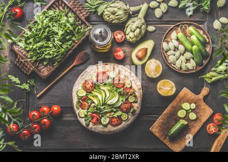 Gesunde Mittagessen Zubereitung. Tortilla Wraps mit frischem Gemüse, Avocado, Olivenöl und Zitrone auf rustikalen Holzküchentisch, Draufsicht. Kochen Stockfoto