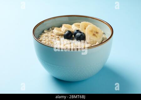 Schüssel mit Haferbrei Haferbrei und Obst auf blauem Hintergrund Stockfoto