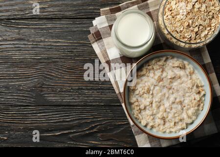 Zusammensetzung mit Haferbrei Brei auf Holzhintergrund. Frühstück wird zubereitet Stockfoto