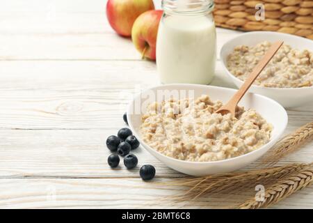 Zusammensetzung mit Haferbrei Haferbrei auf weißem Holzhintergrund. Frühstück wird zubereitet Stockfoto