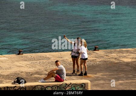 Palmanova, Mallorca, Spanien - 13. April 2019: Tourist lächelt auf Städtereise Urlaub Sightseeing mit Köpfen zusammen, mit Technologie Smartphone nehmen Stockfoto