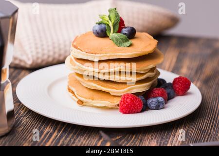 Hausgemachte amerikanische Pfannkuchen mit frischen Heidelbeeren und Himbeeren. Gesundes Frühstück am Morgen. Rustikaler Stil Stockfoto