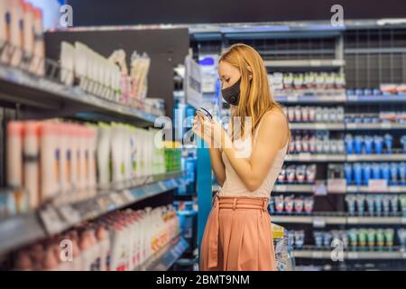 Alarmierte Frau trägt medizinische Maske gegen Coronavirus beim Kauf von Haushaltschemikalien im Supermarkt oder Geschäft - Gesundheit, Sicherheit und Pandemie Stockfoto