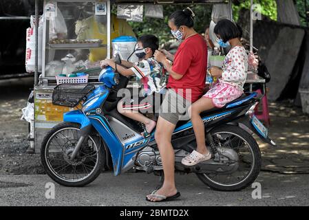 Gesichtsmaske COVID-19 Schutz von Mutter und Kindern getragen. Thailand Street Scene. Südostasien Stockfoto