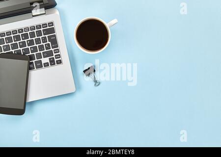 Flaches Lay-Bild des blauen Arbeitsbereichs mit Laptop, Smartphone, Kaffee und Kopierer. Übergeordneter Header-Konzept. Draufsicht. Stockfoto