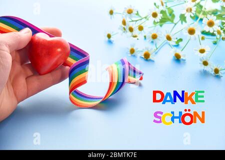 Rotes Herz und Regenbogenband. Der Text 'danke shon' in der deutschen Sprache bedeutet 'Danke' auf Englisch. Symbole der öffentlichen Unterstützung von Ärzten und Kindergärten Stockfoto