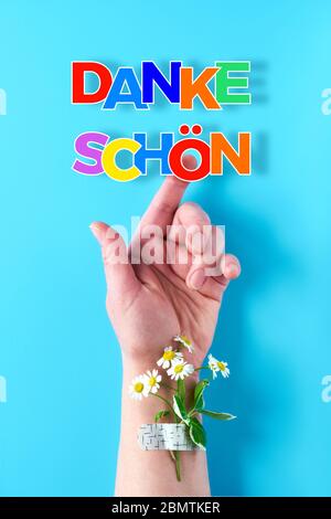 Der Text 'anke shon' bedeutet in deutscher Sprache 'Danke'. Regenbogen Band in der Hand der Frau. Kamille Blume und Gras Bouquet mit medizinischen Hilfe p befestigt Stockfoto