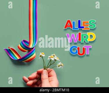 Hand mit Kamillenblüten und Regenbogenband. Symbole der öffentlichen Unterstützung für Ärzte, Krankenschwestern, medizinisches Personal. Text 'alles wird gut' bedeutet 'E Stockfoto