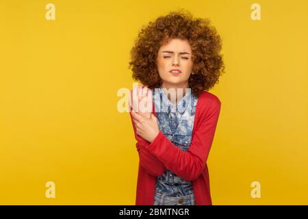 Verletzte Hand. Porträt von jungen Lockenhaarigen Frau winkt in Schmerzen und berühren Wunde Handgelenk, Leiden Gelenkentzündung von rheumatoider Arthritis, Stif Stockfoto