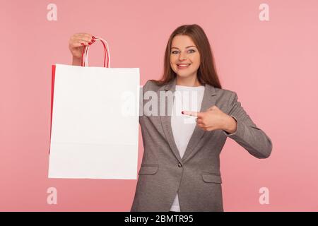 Gute Einkaufsmöglichkeiten! Porträt von glücklich elegante Geschäftsfrau in Anzug Jacke zeigt auf Taschen mit Kopierer Raum für Werbetext, Rabatte und Verkäufe. Stud Stockfoto