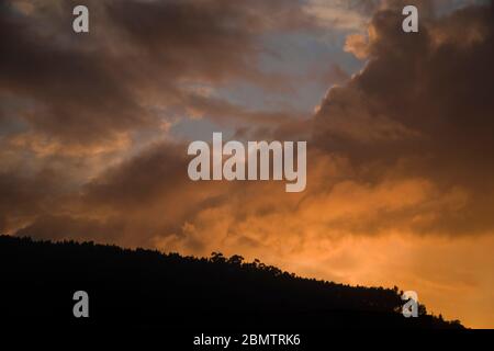 Landschaft nach einem regnerischen Tag, mit großen Wolken, die mit bunten warmen Tönen bei Sonnenuntergang aufleuchten, was eine dramatische und schöne Aussicht Stockfoto