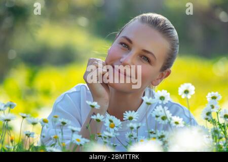 Porträt einer schönen jungen Frau mit Freude verbringen Zeit im Freien, genießen frische Gänseblümchen Blumen auf der Blumenwiese, frohe Frühlingsferien Stockfoto