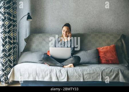 Ein Mädchen arbeitet von zu Hause oder ein Student studiert von zu Hause oder als Freiberufler. Sie verwendet einen Laptop und ein Telefon. Stockfoto