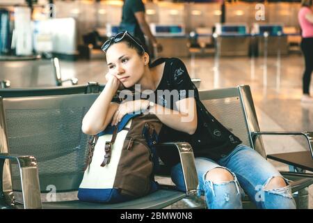 Verärgert oder gelangweilt Mädchen Touristen oder Studenten am Flughafen. Ihr Flug war verspätet oder sie war müde. Stockfoto